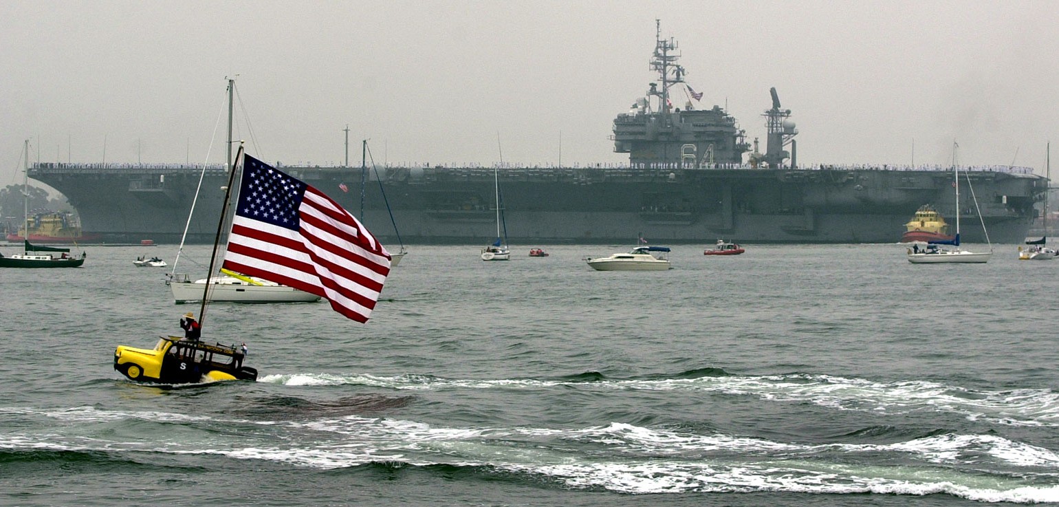 The USS Constellation pulls into San Diego Bay on Monday, June 2, 2003. Dennis St. Onge drives his Woody boatcar in the bay. Photo courtesy of K.C. Alfred U-T