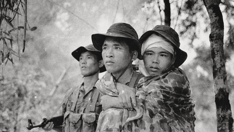 Viet Cong soldier carries a wounded friend
